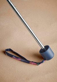 Bastone da passeggio in metallo con al shaft argento, impugnatura in gomma blu e una cinghia in tessuto decorata con motivi floreali e geometrici.