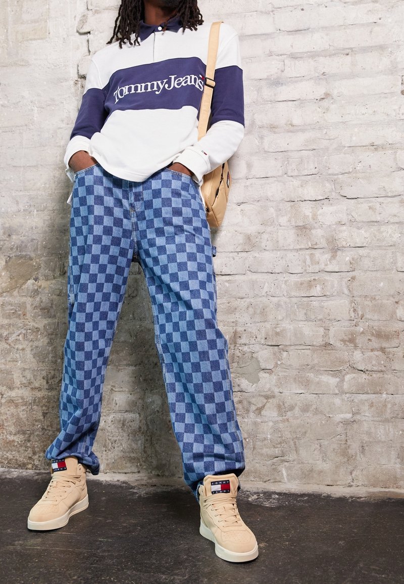 Bílo-náměstná pruhovaná košile s dlouhým rukávem a logem "Tommy Jeans", modré kostkované kalhoty a béžové vysoké tenisky.