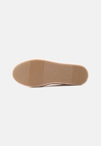 Λαστιχένια σόλα με υφή και σχέδιο επιφάνειας. Το παπούτσι έχει στρογγυλεμένο σχήμα και ανοιχτό ροζ επάνω μέρος με λεπτές λεπτομέρειες σαν γούνα.