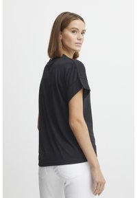 Svart kortärmad t-shirt i mjuk tyg, med avslappnad passform och rund halsringning. Slät yta med uppvikta ärmar.