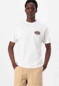 Hvit bomulls T-skjorte med et fargerikt brodert design av et hodeskalle med sombrero. Korte ermer og rund hals.