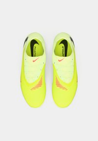 Vibrantne žute nogometne kopačke s teksturiranim sintetičkim gornjim dijelom, crnim Nike logotipom i ružičastim naglascima. Ima sustav vezanja za sigurno pristajanje.