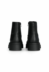 Stivali alla caviglia in pelle nera con una texture liscia, dotati di una suola in gomma spessa e cerniere sul retro per una facile calzata. Logo del marchio sulla suola.