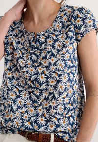 Navy blouse made of lightweight fabric featuring a white daisy pattern with orange centers. Short sleeves and a round neckline with pleats.