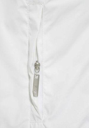 Balta jaka ar rāvējslēdzēja kabatu un sudraba rāvējslēdzēju, ar teksturētu audumu un smalkiem šuvumu detaļām.