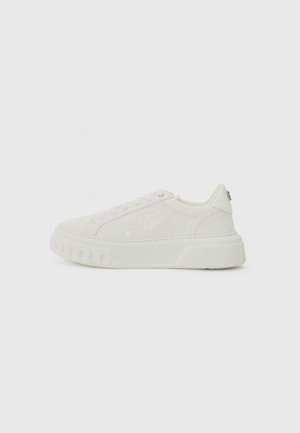 White sneaker with textured leather upper, round toe, and thick sole. Features subtle logo on the heel and lace-up front with flat laces.