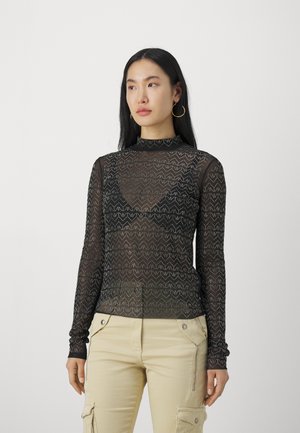 Zwart mesh shirt met lange mouwen, voorzien van een zigzagpatroon, hoge halslijn en aansluitend ontwerp, gecombineerd met beige cargobroek.
