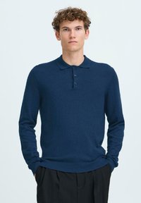 Polo de manga larga en azul marino, hecho de un tejido de punto suave, con tapeta de tres botones y puños y dobladillo acanalados.
