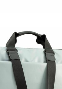 Bolso gris claro con asas negras, con una textura suave, forma rectangular y un asa superior para un fácil transporte.