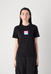 Black cotton t-shirt with a round neckline, featuring a square logo in pink, light blue, and white on the center front. Classic fit.