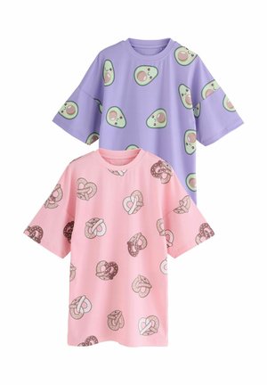 Due t-shirt overdimensionati: uno lavanda con stampe di avocado, e uno rosa con design di pretzel. Entrambi realizzati in tessuto morbido e liscio.