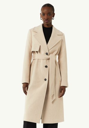 Beige wolmix jas met een brede revers, ceintuur op de taille en dubbel knopen. Beschikt over zijzakken en een middenlange uitstraling.
