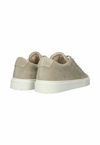 Svetlo béžové semišové tenisky s hrubými bielymi gumovými podrážkami, pohľad zozadu, zobrazujúce polstrované golieriky a šnurovanie.