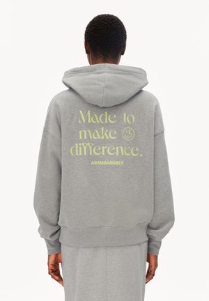 Person trägt einen grauen Hoodie mit heruntergelassener Kapuze, Text "Made to make difference. ARMEDANGELS" in hellgrün auf dem Rücken gedruckt.