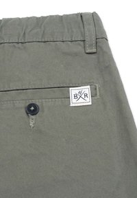 Gröna bomullsshorts har en elastisk midja, bakficka med knappstängning och ett broderat varumärkesmärke.