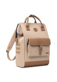 Beige canvas rugzak met bruine leren accenten, sluiting met voorflap, bovenhandvatten, verstelbare schouderriem en zijvakken.