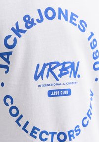 Camiseta blanca de algodón con texto gráfico azul. El diseño incluye "JACK & JONES 1990 URBN." y "COLLECTORS CREW" en fuentes negritas.