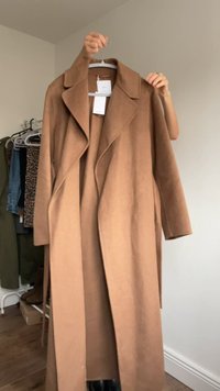 Brown wool blend overcoat with a notched collar, open front, and long sleeves. Textured fabric and hanging care tags visible.