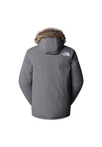 Grå isolerad jacka med pälsfodrad huva, broderad logotyp på baksidan och en slät yta. Designad för utomhusbruk.
