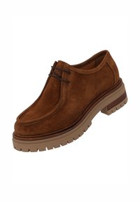 Scarpa in suede marrone con design ispirato ai mocassini, punta tonda e suola in gomma marrone con battistrada texturizzato per una maggiore aderenza.