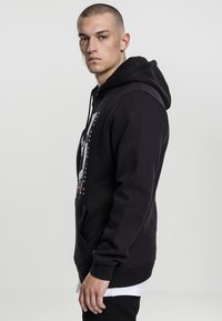 Sudadera con capucha negra, con bolsillo frontal y un diseño gráfico. Tela suave, corte regular, con puños y dobladillo acanalados.