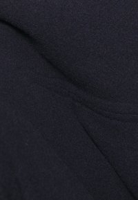 Tissu bleu marine foncé avec une texture lisse, présentant des lignes et des plis subtils. Fabriqué à partir d'un matériau doux, semblable à du feutre, convient à diverses utilisations.