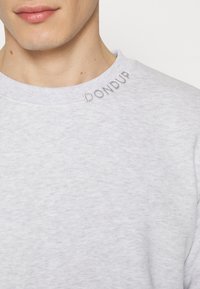 Jasnoszara bluza z teksturowanej tkaniny, z subtelnym haftem "DON DUP" na kołnierzu. Prosty dekolt typu crew neck.