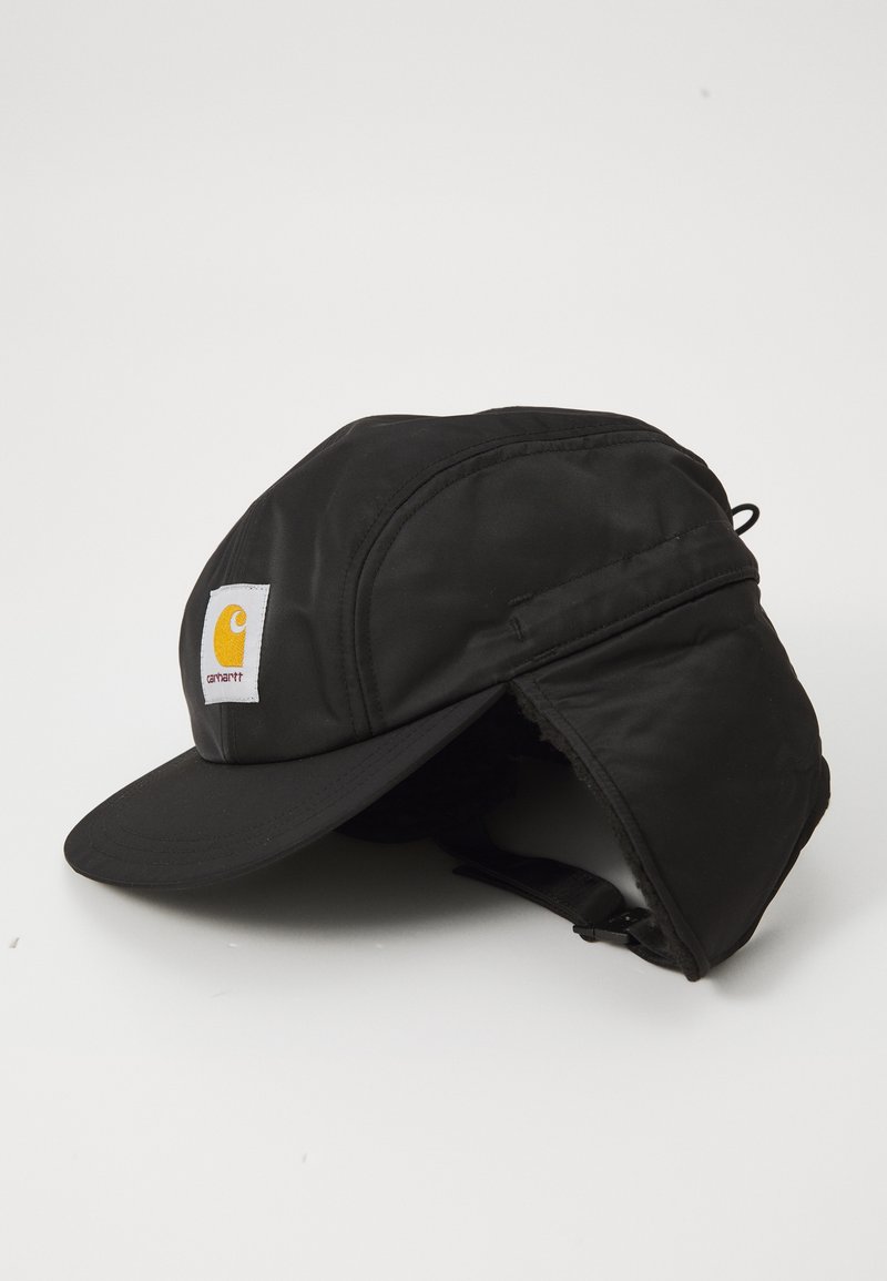 Zwarte geïsoleerde pet met een gebogen rand, voorzien van een fleece-aangedekte oorflap en een wit-geel Carhartt-logo aan de voorkant.