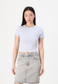 Lichtgrijze fitted t-shirt met korte mouwen en een ronde halslijn, gecombineerd met een denim potloodrok met een vervaagd patroon.