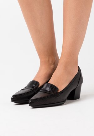 Talons en cuir noir avec une surface texturée, bout pointu et un petit talon carré ; présente un détail de sangle horizontale sur le devant.