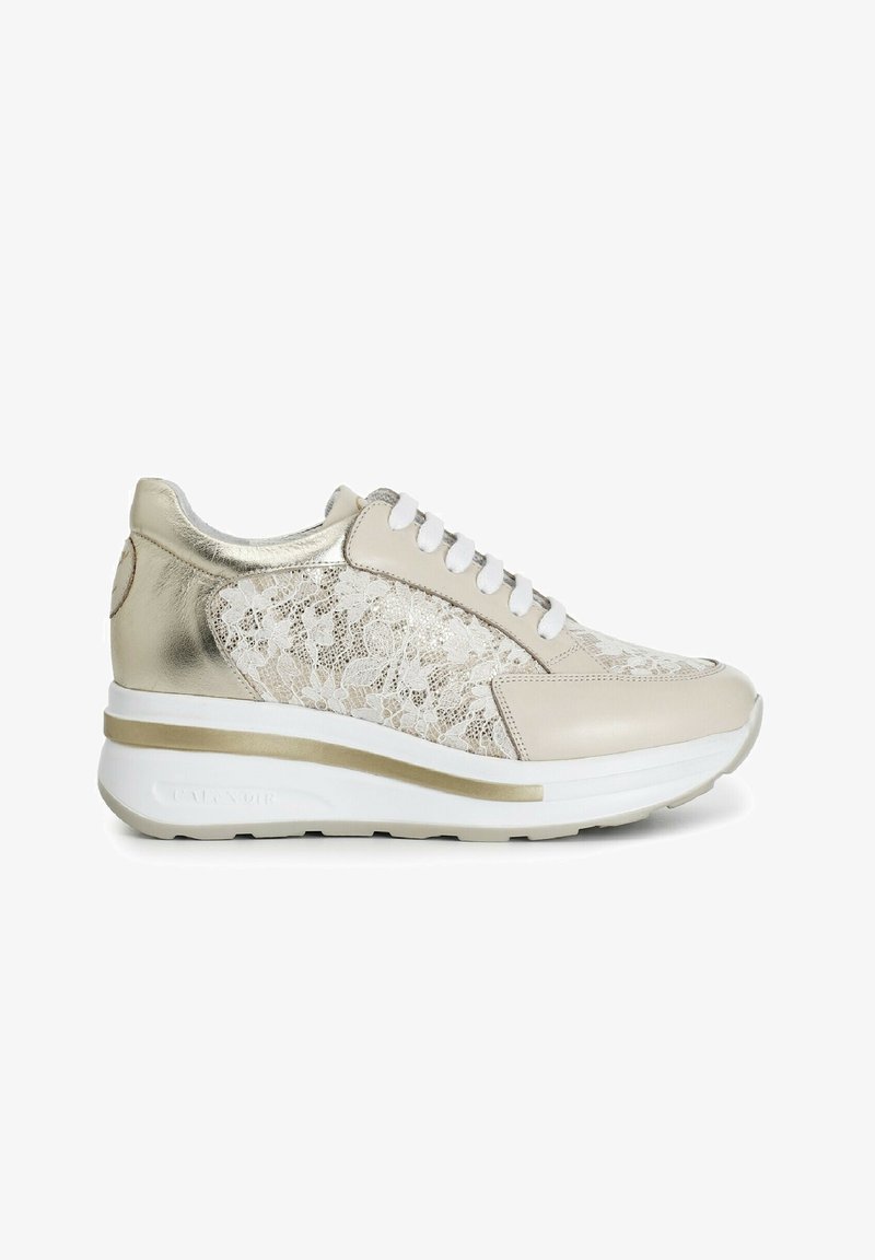 Sneaker beige con lacci, con un accento metallico dorato, sovrapposizione di pizzo testurizzato e suola bianca con una striscia dorata.