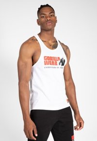 Bela majica brez rokavov z rdečim in črnim grafičnim napisom "GORILLA WEAR", okroglim ovratnikom, v kombinaciji s črnimi hlačami s logotipom.