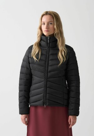Schwarze gepolsterte Jacke mit hohem Kragen, ausgestattet mit einem Karo-Steppdesign, Frontreißverschluss und langen Ärmeln. Getragen über einem burgunderfarbenen Rock.