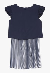 Námořnická modrá šaty se hladkým, přiléhavým tělem, s volánkovými rukávy a skládací sukní se bílými a námořnickými pruhy. Zapínání na zadním zipu.