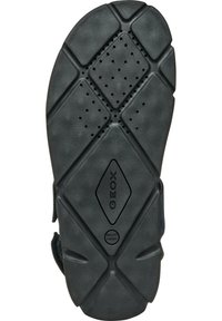 Suola di scarpa in gomma nera con una superficie texture caratterizzata da un motivo geometrico, perforazioni per la traspirazione e un logo centrale.