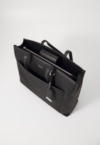 Sac à main en cuir noir avec un motif texturé foncé, ouverture zippée, poignées supérieures et une poche avant avec une étiquette. Compartiments intérieurs visibles.