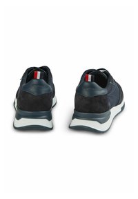 Marineblauwe sportschoenen van een combinatie van gestructureerde stof en suede, met een witte zool en een rode, witte en blauwe accent op de hiel.