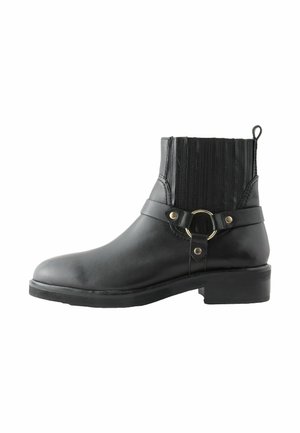 Juodas odinis kulkšninis batas su apvaliu pirštu, akcentuotas auksiniu apvaliu sagtimi ir vertikaliomis briaunomis ant liemens. Žemas bloko kulnas.