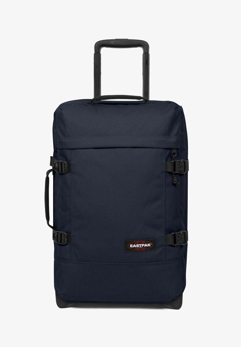 Námořnický modrý batoh na kolečkách vyrobený z odolné tkaniny, s teleskopickou rukojetí, bočními popruhy a značkovou nášivkou na přední straně.