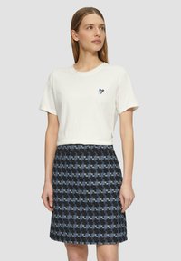 Witte katoenen t-shirt met een klein blauw hartgrafiek, gecombineerd met een rok van middelgrote lengte met een blauw en zwart houndstooth patroon, van textuurstof.