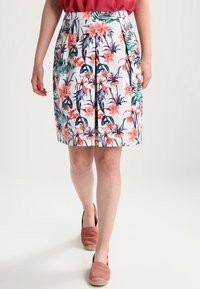 Jupe à imprimé floral présentant des motifs roses, verts et marine sur un fond blanc, avec un design plissé et une coupe hauteur genoux.