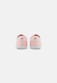 Pink canvas sneakers with a textured finish, white rubber sole, and small logo accent on the heel. Rear view shows a simple design.