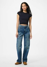 Crni kratki majica, uskog kroja; uparen s visokim strukom, širokim plavim trapericama s laganim pranjem i vidljivim šavovima.