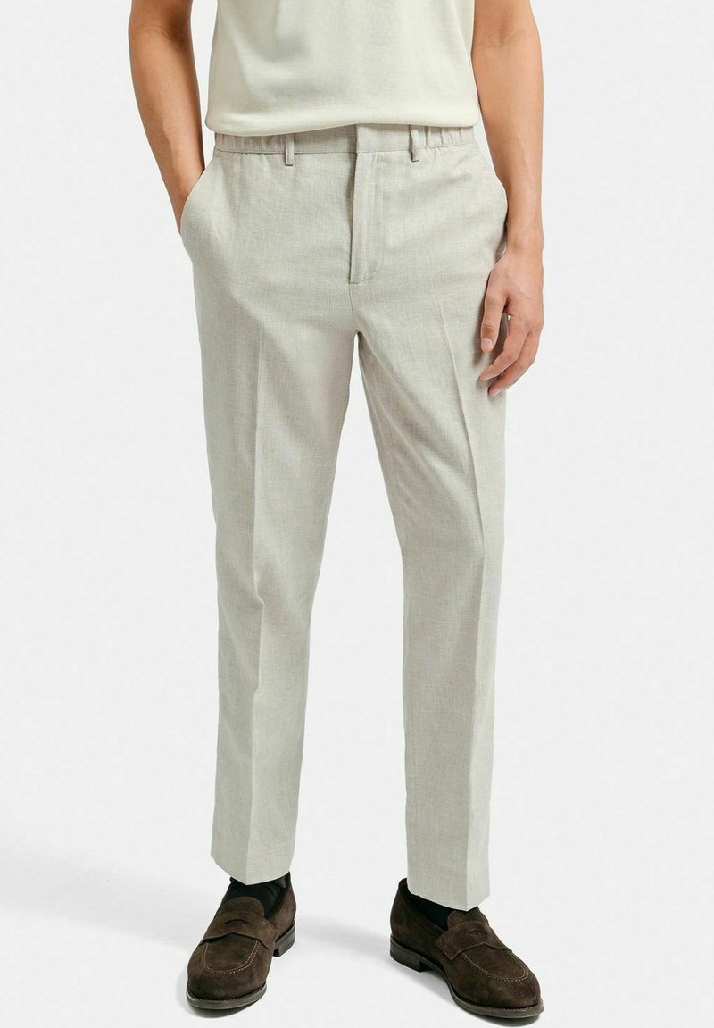 Ljust grå byxor med skräddarsydd passform, tillverkade av ett mjukt tyg. Har flat front, sidfickor och en veck ner längs benen.