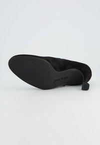 Chaussure en daim noir avec un bout lisse et arrondi, au design épuré. Dispose d'une semelle extérieure rembourrée avec le nom de la marque en relief.