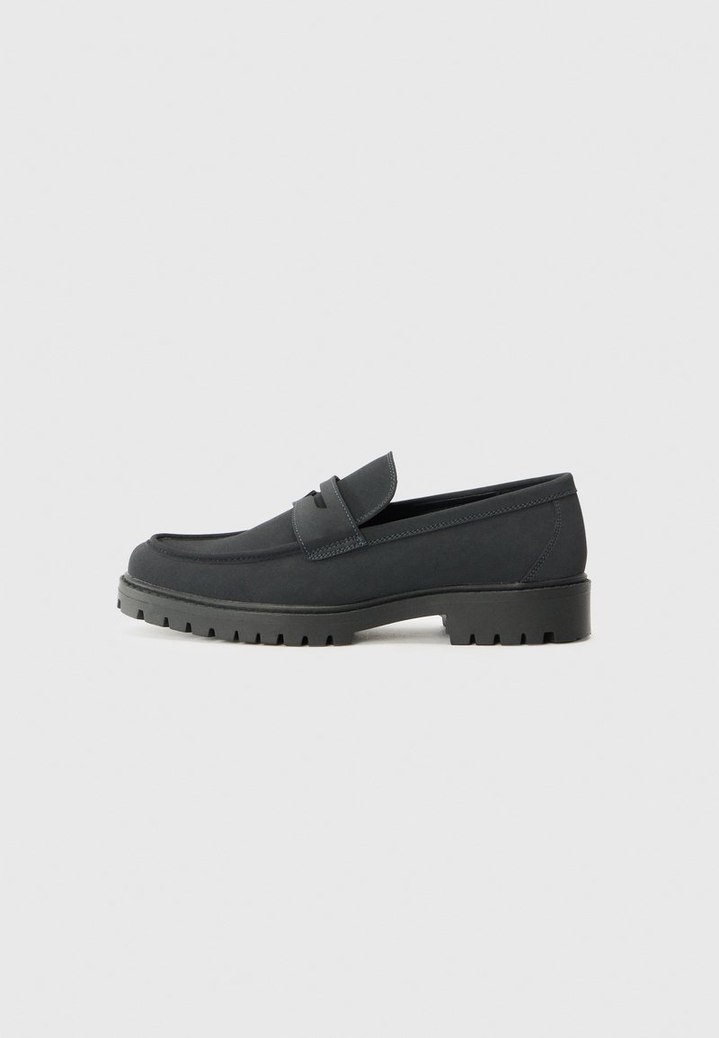 Sorte loafersko med en glat, mat finish, med en rund tå og en tyk, struktureret sål. Udsmykket med en frontrem.