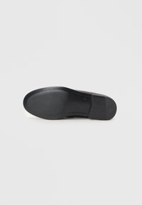 Semelle de chaussure noire avec une surface texturée, un design courbé et un léger talon ; matériau en caoutchouc avec des accents lisses et à motifs.