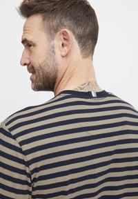 Kurzärmliges gestreiftes T-Shirt mit beigen und marineblauen horizontalen Streifen, Rundhalsausschnitt und einem kleinen Schlaufenetikett auf der Rückseite.
