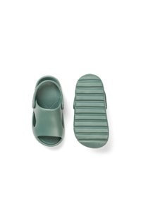 Zöld gumis szandál nyitott orral és oldalsó kivágásokkal. Texturált talpbetét és mintázott bordás talp a tapadásért és a kényelemért.