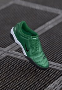 Zelená kožená sportovní bota s texturovaným povrchem, černým swooshem Nike a bílou podrážkou; má šněrovací design a polstrovaný límec.